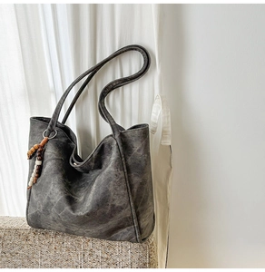 Detail of charcoal grey tote bag with washed texture and wooden beaded tassel charm