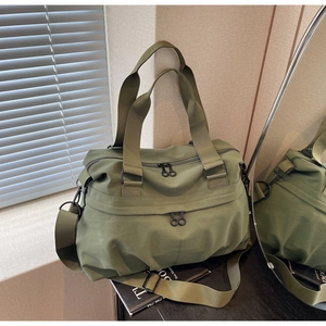 Detail of olive green nylon tote bag with adjustable strap in natural light setting