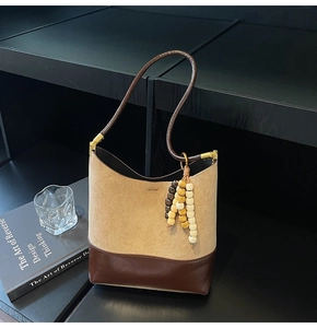 Détail du sac cabas en daim et cuir marron avec gland en perles et boucles dorées