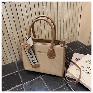 Détail d'un sac bandoulière en toile beige avec bordure en cuir marron et sangle