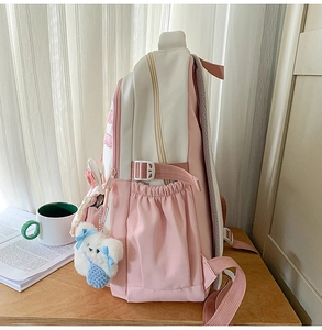 Detail view of pink and beige canvas backpack with plush bear charm and side buckle strap