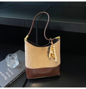 Détail du sac en daim kaki avec bordure en cuir marron et perles en bois décoratives