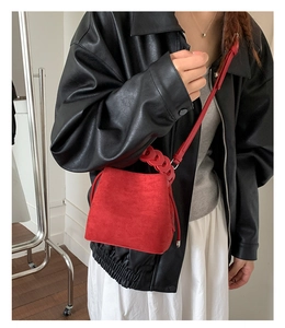 Detail of red suede bucket bag with matching strap and decorative chunky chain handle
