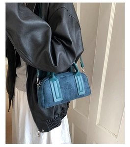 Detailed view of navy blue suede bowling bag with teal handles and shoulder strap