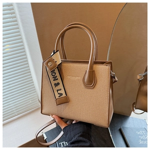Détails des finitions en cuir brun sur le sac en tissu beige avec pendentif ION & LA