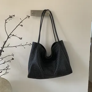 Vue détaillée du sac cabas en cuir tressé noir avec d'élégantes bretelles fines