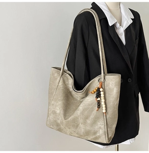 Detail of vintage large tote bag with wooden bead pendant on shoulder strap and textured fabric