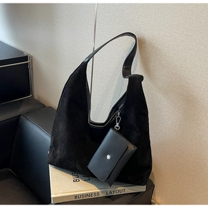 Minimalist black faux suede Hobo shoulder bag with detachable mini pouch on a leather chair