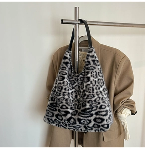 Close-up of black and white leopard print faux fur tote bag hanging with autumn outfits