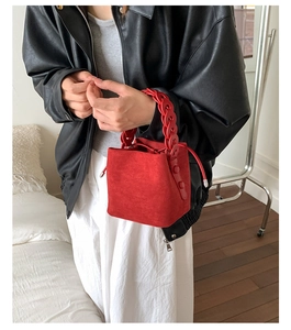 Detail of red suede bucket bag with chain handle and drawstring closure shown on model
