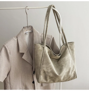 Detail of olive green tote bag with magnetic clasp and double straps on white hanger