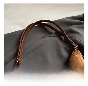Détail du sac vintage marron mat avec breloque perlée et fermeture dorée sur tissu