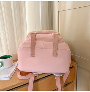 Detailed close-up of pink school backpack with white lace trim and sturdy straps