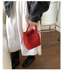 Detail of red suede bucket bag with chunky chain handle and drawstring closure