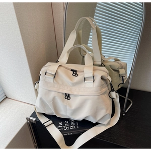 Close-up of beige nylon tote bag with black zipper detail and adjustable strap