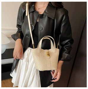 Dettaglio borsa a secchiello intrecciata beige con chiusura dorata e tracolla regolabile