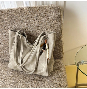 Detail view of large charcoal tote bag with ethnic bead tassel on woven seat