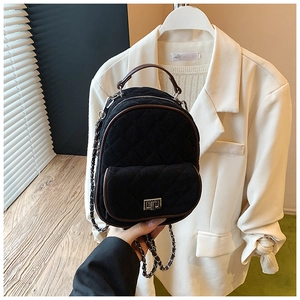 Close-up of black quilted mini backpack with brown leather trim and silver metal twist lock