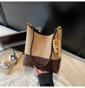 Détail du sac cabas en daim et cuir avec pendentif en perles de bois et boucles dorées