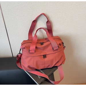 Macro detail of terracotta nylon tote bag featuring front dual zipper pockets and ring pulls