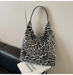 Detail of faux fur leopard print tote bag with black leather strap on a minimal background