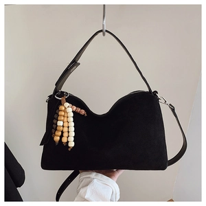Detail of black suede crescent bag featuring colorful wooden bead tassels and strap