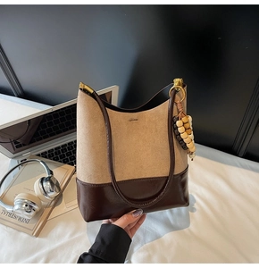 Détail du sac cabas bicolore en daim beige et cuir marron avec pendentif en perles