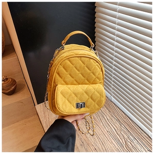 Detailed shot of yellow quilted mini backpack with silver chain and metal turn-lock