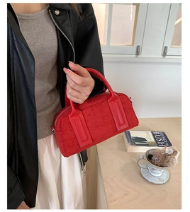 Close-up of a red suede Boston handbag with a textured finish and dual handles