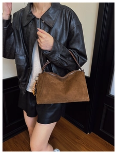 Close-up of brown suede hobo bag featuring decorative wood and ceramic beads