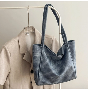 Detail view of a large blue-grey washed leather tote bag with long slim shoulder straps