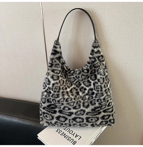 Macro shot of faux fur leopard print texture and black leather strap on a shoulder bag