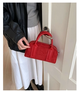 Close-up of red suede boston bag with dual handles and metal zipper detail