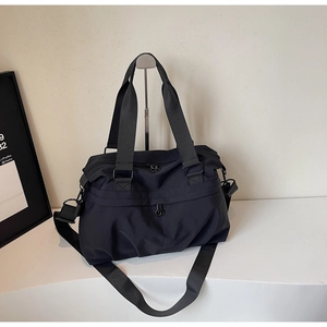 Detail of a large black nylon travel bag with adjustable strap and sturdy double handles
