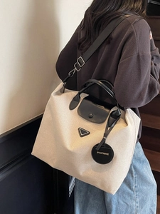 Large beige canvas tote bag with black leather handles and detachable shoulder strap