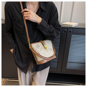 Détail du sac seau à bandoulière avec imprimé lettres, cuir crème et marron et ferrures dorées