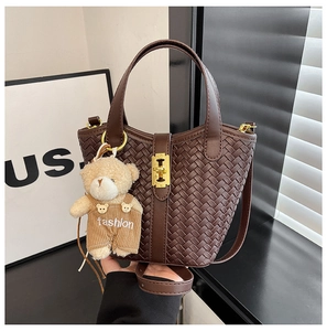 Dettaglio della borsa a secchiello intrecciata marrone con chiusura oro e orsetto
