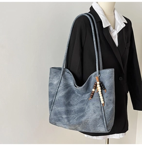 Blue denim texture tote bag with wooden bead charm styled on a black professional blazer