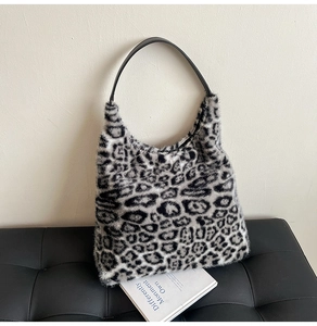 Detailed view of plush leopard print hobo bag texture and leather strap on a black bench