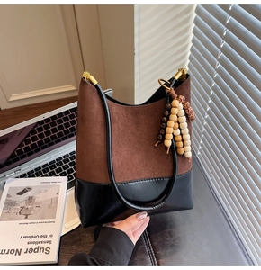 Détail du cabas en daim mat et cuir lisse avec pompon perlé vintage et ferrures dorées