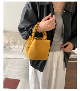 Detail of ginger yellow suede bucket bag with chunky braided handle and drawstring