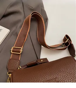 Détail du sac Boston en cuir marron avec bandoulière en nylon réglable et gaufrage mode