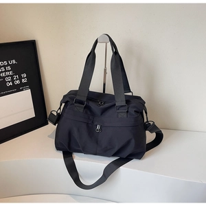 Detailed close-up of durable black nylon tote bag with metal zippers and shoulder strap