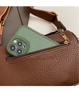 Gros plan d'un sac en cuir marron avec poche zippée contenant un smartphone