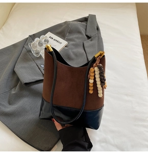 Détail de la texture en daim marron et noir brillant du sac avec pendentif en bois