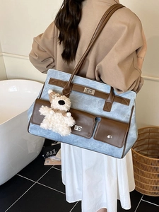 Large blue tote bag with brown leather trim and cute plush bear charm on model back