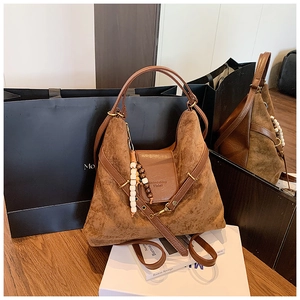 Détail du sac hobo marron mat avec pendentif en perles de bois et logo embossé