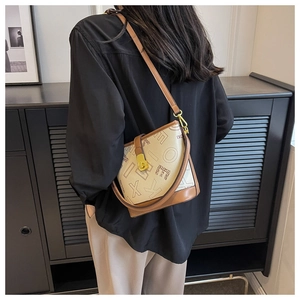Détail d'un sac seau vintage avec motif logo en toile beige et finitions en cuir brun