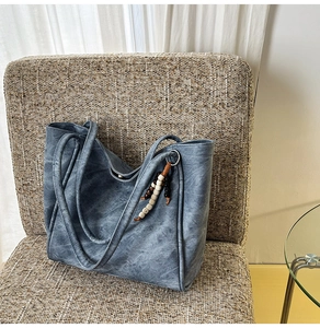 Detailed view of the vintage grey-blue tote bag texture with beaded pendant on a chair