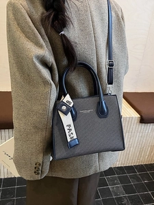 Petit sac carré bleu marine texturé avec bandoulière porté par un mannequin en costume chic